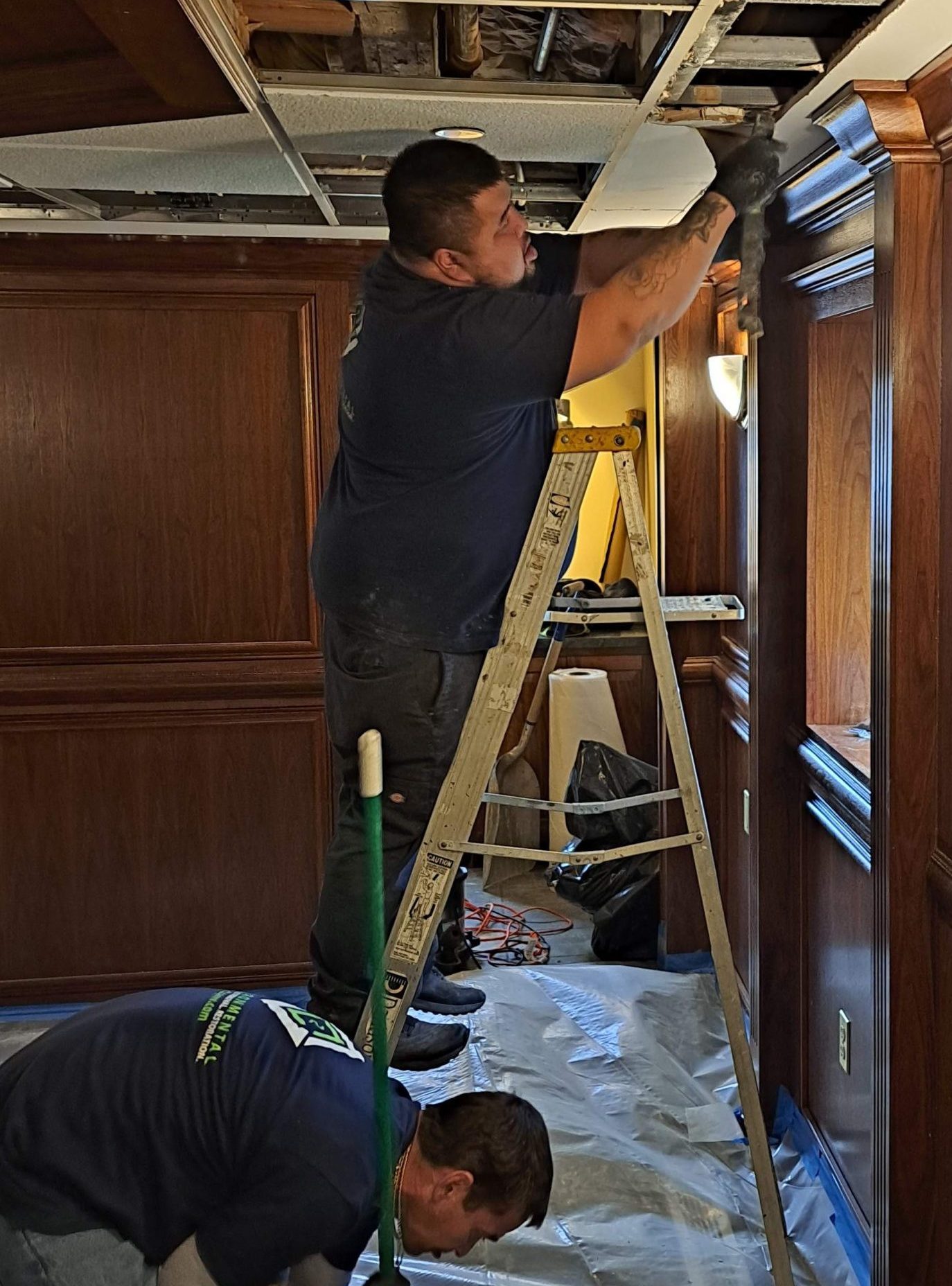 C2G technicians removing water-damaged ceiling tiles over protective plastic sheeting