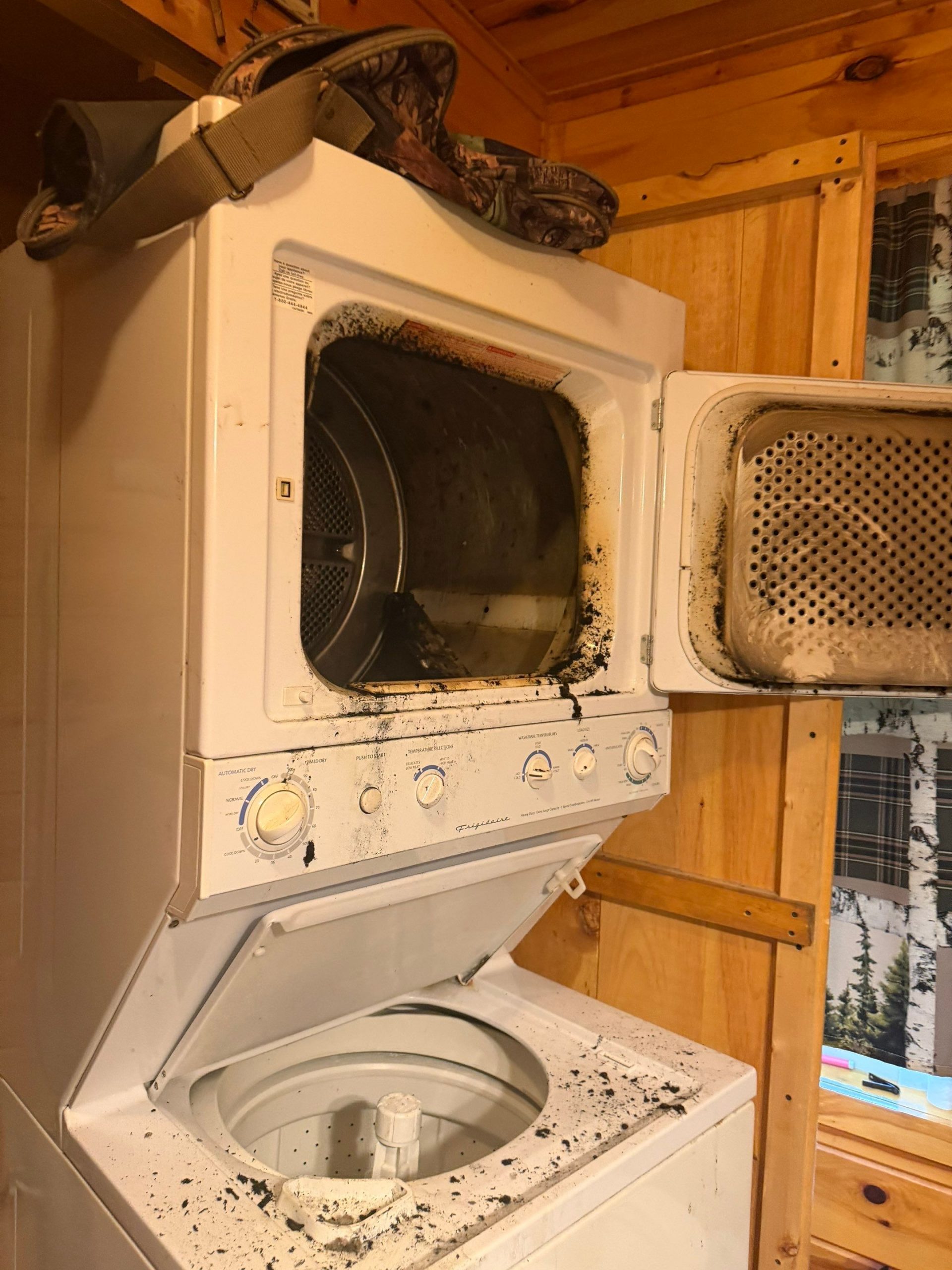 Stacked washer dryer with charred lint and fire damage inside dryer opening