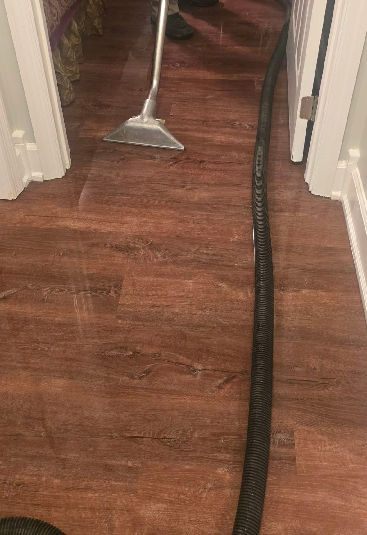 C2G technician using a floor vacuum to extract water from a wood floor