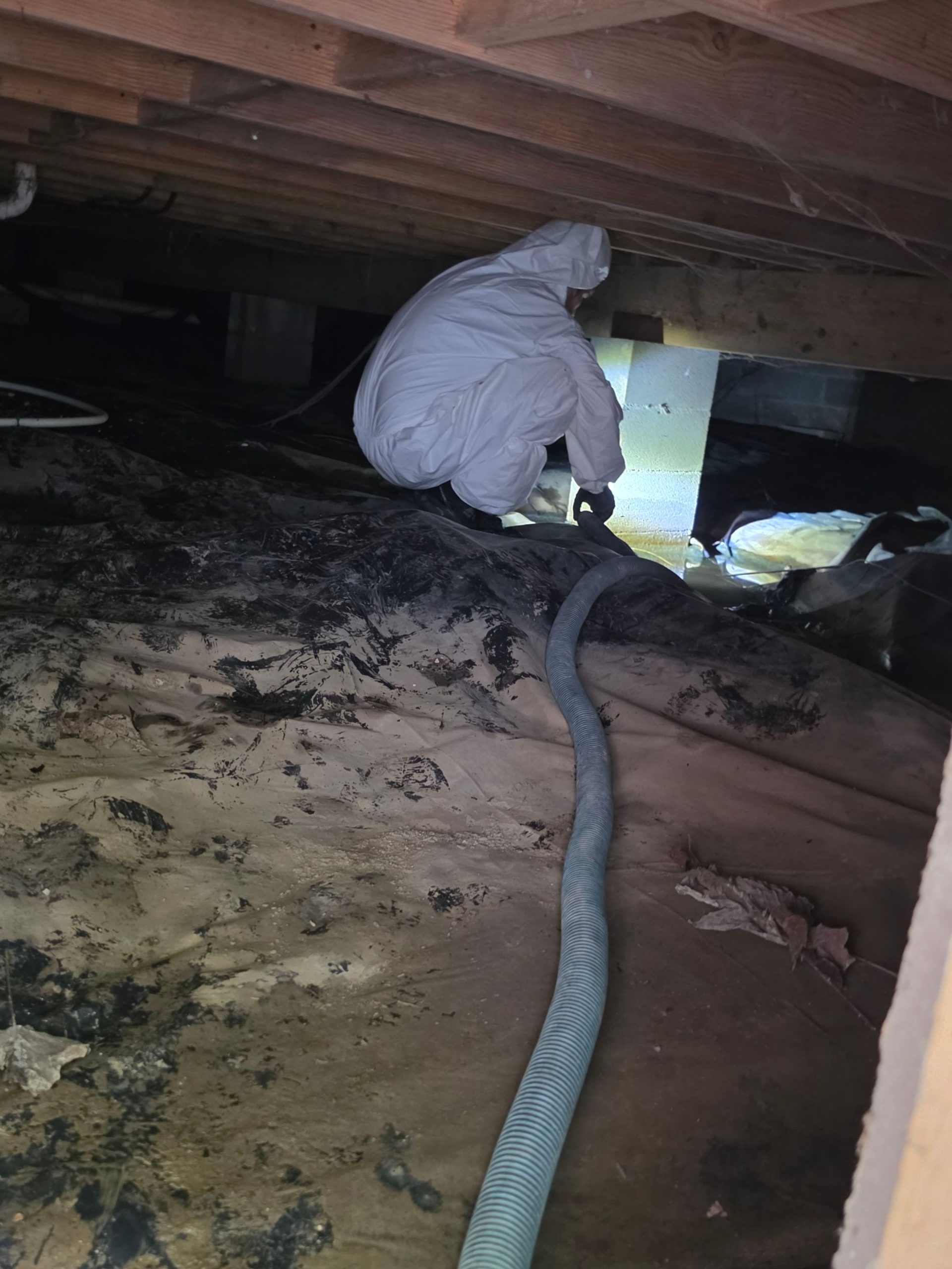 C2G technician in PPE extracting standing water from a crawlspace