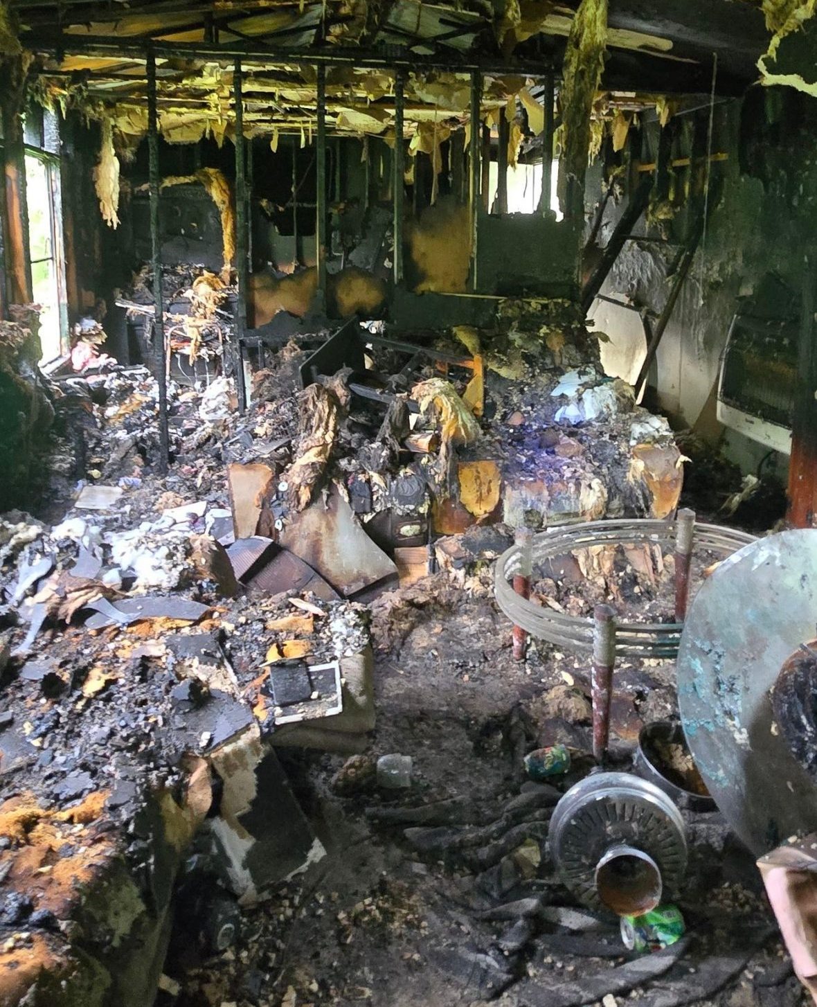 Completely fire-damaged trailer with charred belongings and destroyed interior