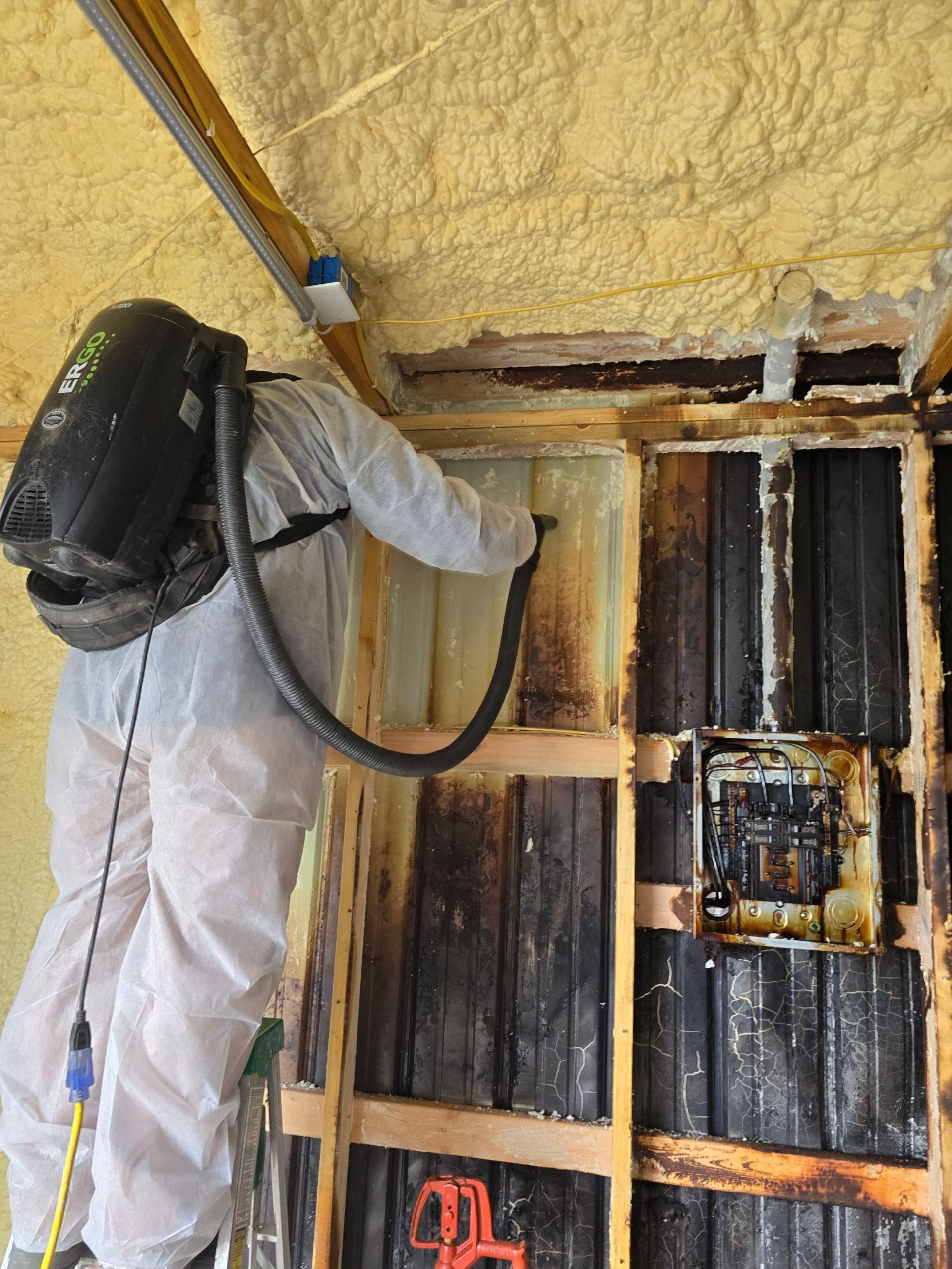 C2G technician using a backpack vacuum to remove soot from a fire-damaged wall