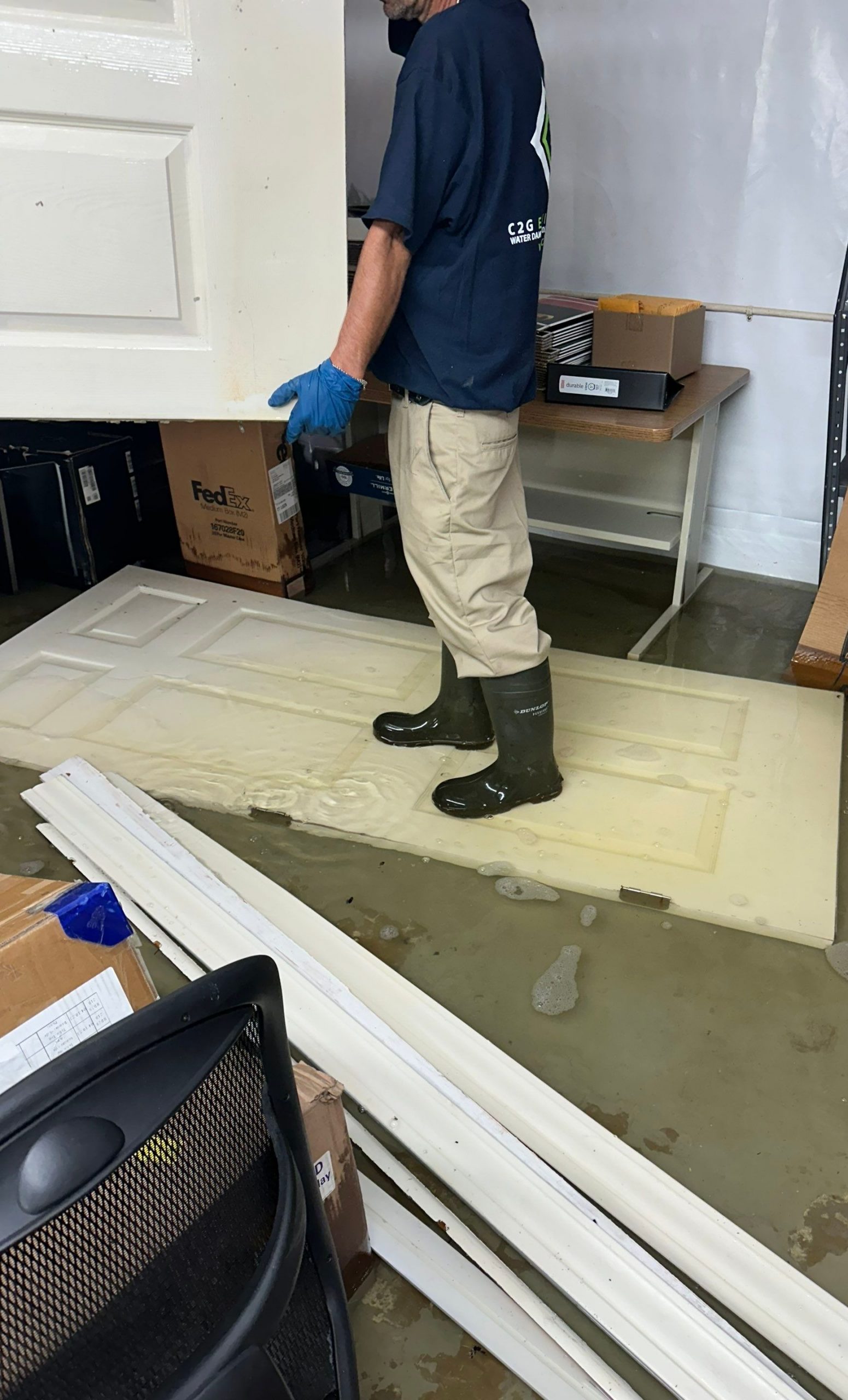 C2G technician in boots and gloves removing a door from a flooded room