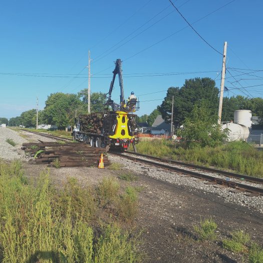 C2G hi-rail grapple truck loading railroad ties from trackside