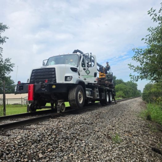 C2G hi-rail grapple truck traveling on railroad tracks