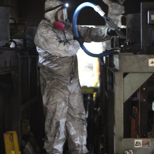 C2G technician in PPE and respirator vacuuming soot from industrial equipment