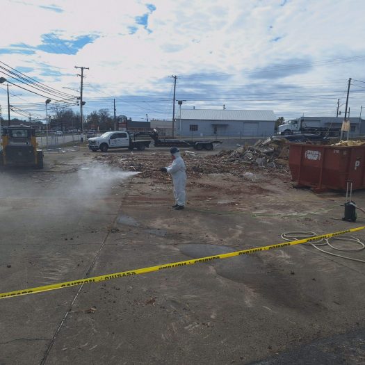 C2G Environmental technician spraying the ground and surroundings to keep asbestos from going airborne