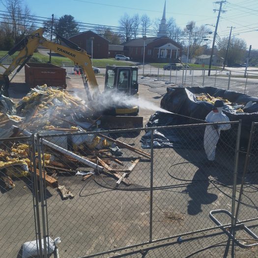 C2G Environmental technician spraying the ground and surroundings to keep asbestos from going airborne