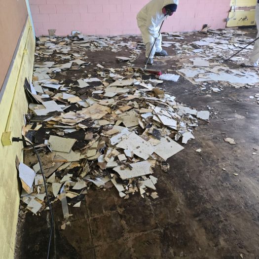 C2G Environmental technician removing asbestos floor tile during an abatement project