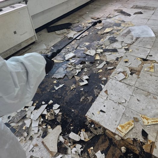 C2G Environmental technician removing asbestos floor tile during an abatement project