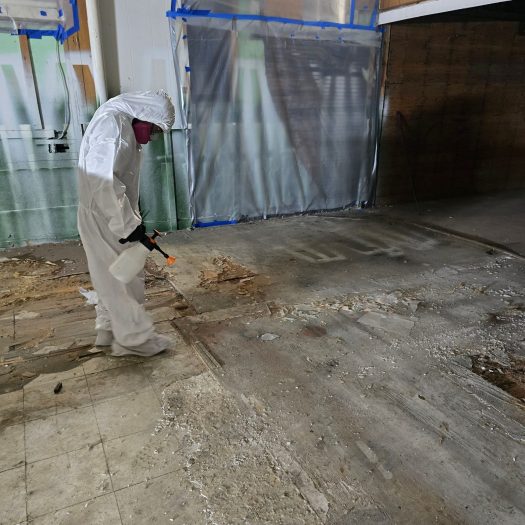 C2G Environmental technician spraying the ground and surroundings to keep asbestos from going airborne