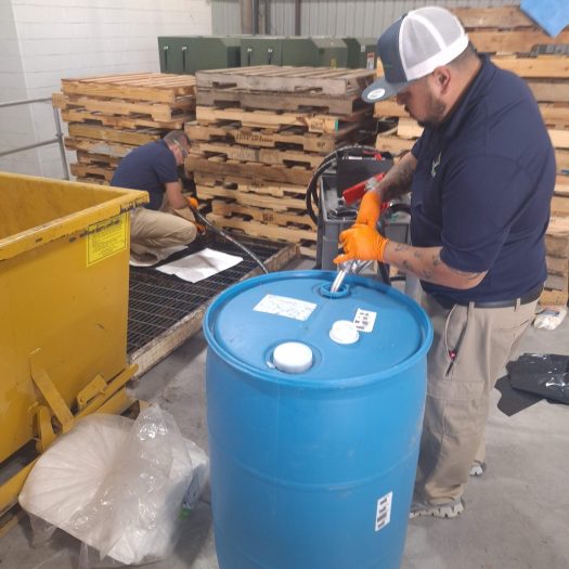 C2G technicians pumping chemical liquid from a basin into a blue barrel