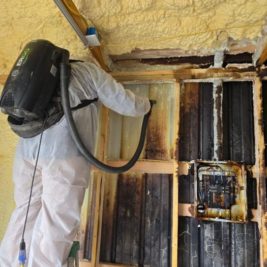 C2G technician using a backpack vacuum to remove soot from a fire-damaged wall