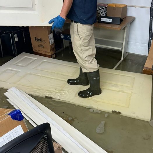 C2G technician in boots and gloves removing a door from a flooded room