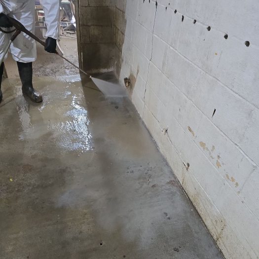 C2G technician pressure washing mud from walls and floors after flooding