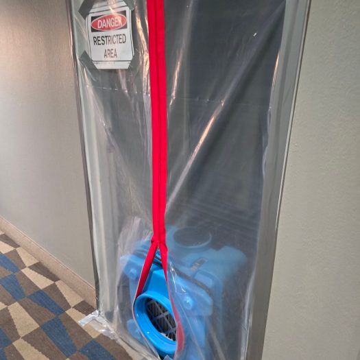 Air filtration fan outside a sealed containment area with Danger Restricted Area sign